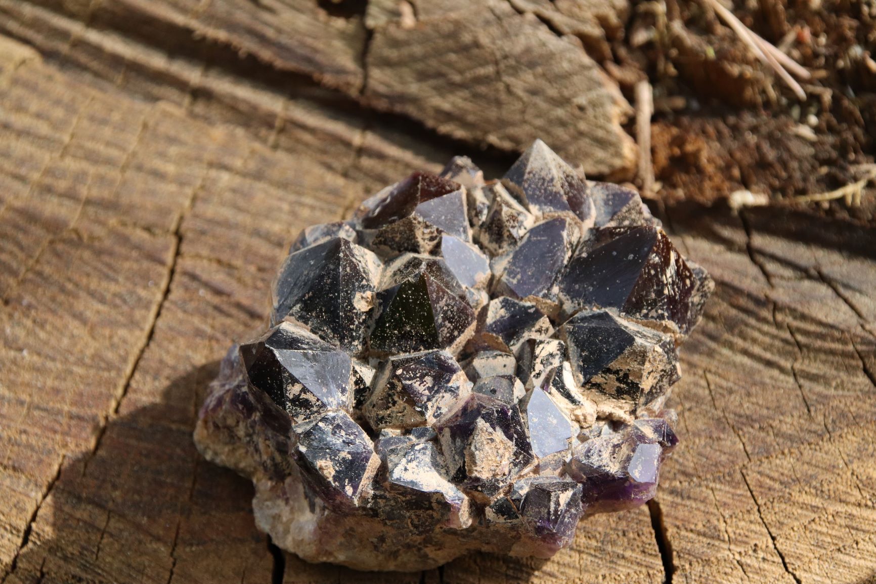 Piece of crystallized amethyst on a raw wooden plate.
